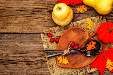 Sonbahar sofrası. Şükran Günü ya da Cadılar Bayramı. Yaprak şeklinde seramik tabak, siyah çatal bıçak takımı, balkabağı ve köpek gülü böğürtlenleri. Eski tahta arka plan, üst görünüm