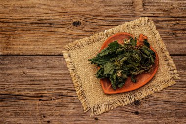 Kuru yapraklar ve ısırgan otu çiçekleri. Sağlıklı çay ve alternatif ilaç pişirmek için bitkisel malzeme. Eski tahta arka plan, üst görünüm