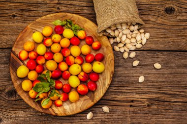 Olgun vişneli erik hasadı. Çuvalda meyve ve tohum çeşitleri var. Eski tahta arka plan, üst görünüm