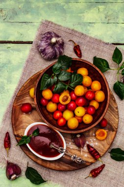 Sarımsaklı ve acı biberli Tkemali Gürcü kiraz sosu. Olgun meyve ve baharatlardan geleneksel sos. Yumuşak yeşil ahşap arka plan, kapat