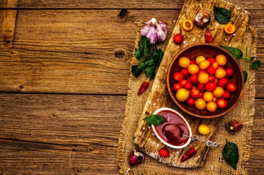 Sarımsaklı ve acı biberli Tkemali Gürcü kiraz sosu. Olgun meyve ve baharatlardan geleneksel sos. Vintage ahşap arkaplan, üst görünüm
