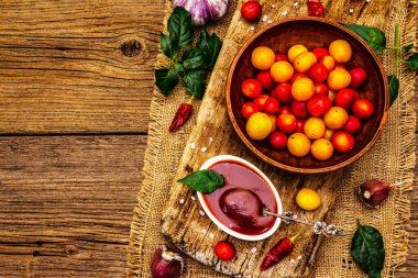 Sarımsaklı ve acı biberli Tkemali Gürcü kiraz sosu. Olgun meyve ve baharatlardan geleneksel sos. Vintage ahşap arkaplan, üst görünüm