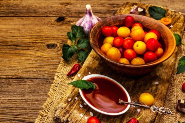 Sarımsaklı ve acı biberli Tkemali Gürcü kiraz sosu. Olgun meyve ve baharatlardan geleneksel sos. Vintage ahşap arkaplan, kopyalama alanı