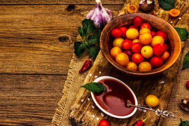 Sarımsaklı ve acı biberli Tkemali Gürcü kiraz sosu. Olgun meyve ve baharatlardan geleneksel sos. Vintage ahşap arkaplan, kopyalama alanı