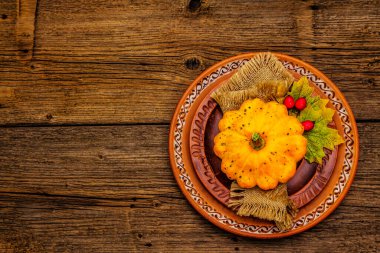 Sonbahar ve Şükran Günü yemeği. Balkabağı ve böğürtlen hasadı, renkli yapraklar, seramik tabaklar ve eski peçete. Çatal bıçak takımı ahşap arka plan, üst görünüm