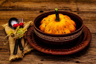 Sonbahar ve Şükran Günü yemeği. Balkabağı ve böğürtlen hasadı, renkli yapraklar, seramik tabaklar, çatal ve kaşık, antika peçete. Çatal bıçak takımı ahşap arka plan, kapat