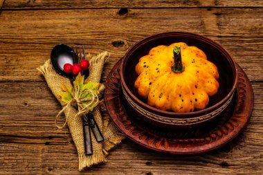 Sonbahar ve Şükran Günü yemeği. Balkabağı ve böğürtlen hasadı, renkli yapraklar, seramik tabaklar, çatal ve kaşık, antika peçete. Çatal bıçak takımı ahşap arka plan