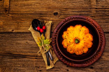 Sonbahar ve Şükran Günü yemeği. Balkabağı ve böğürtlen hasadı, renkli yapraklar, seramik tabaklar, çatal ve kaşık, antika peçete. Çatal bıçak takımı ahşap arka plan, üst görünüm