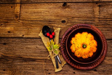 Sonbahar ve Şükran Günü yemeği. Balkabağı ve böğürtlen hasadı, renkli yapraklar, seramik tabaklar, çatal ve kaşık, antika peçete. Çatal bıçak takımı ahşap arka plan, üst görünüm