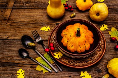 Sonbahar ve Şükran Günü yemeği. Balkabağı ve böğürtlen hasadı, renkli yapraklar, seramik tabak ve kase, çatal, kaşık ve meşe palamudu. Çatal bıçak takımı ahşap arkaplan, kopyalama alanı