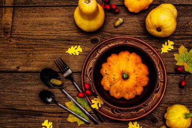 Sonbahar ve Şükran Günü yemeği. Balkabağı ve böğürtlen hasadı, renkli yapraklar, seramik tabak ve kase, çatal, kaşık ve meşe palamudu. Çatal bıçak takımı ahşap arka plan, üst görünüm