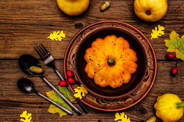 Sonbahar ve Şükran Günü yemeği. Balkabağı ve böğürtlen hasadı, renkli yapraklar, seramik tabak ve kase, çatal, kaşık ve meşe palamudu. Çatal bıçak takımı ahşap arka plan, üst görünüm