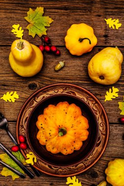 Sonbahar ve Şükran Günü yemeği. Balkabağı ve böğürtlen hasadı, renkli yapraklar, seramik tabak ve kase, çatal, kaşık ve meşe palamudu. Çatal bıçak takımı ahşap arka plan, üst görünüm