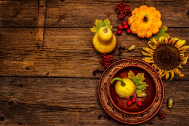 Sonbahar ve Şükran Günü yemeği. Balkabağı ve böğürtlen hasadı, renkli yapraklar, seramik tabak ve kase, ayçiçeği ve rowan. Çatal bıçak takımı ahşap arka plan