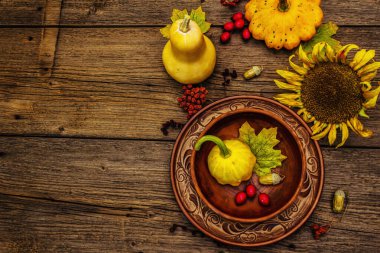 Sonbahar ve Şükran Günü yemeği. Balkabağı ve böğürtlen hasadı, renkli yapraklar, seramik tabak ve kase, ayçiçeği ve rowan. Çatal bıçak takımı ahşap arka plan