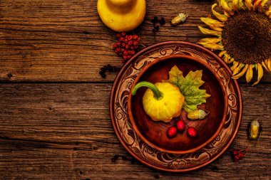 Sonbahar ve Şükran Günü yemeği. Balkabağı ve böğürtlen hasadı, renkli yapraklar, seramik tabak ve kase, ayçiçeği ve rowan. Çatal bıçak takımı ahşap arka plan