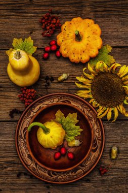 Sonbahar ve Şükran Günü yemeği. Balkabağı ve böğürtlen hasadı, renkli yapraklar, seramik tabak ve kase, ayçiçeği ve rowan. Çatal bıçak takımı ahşap arka plan