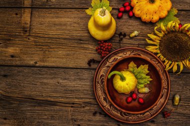 Sonbahar ve Şükran Günü yemeği. Balkabağı ve böğürtlen hasadı, renkli yapraklar, seramik tabak ve kase, ayçiçeği ve rowan. Çatal bıçak takımı ahşap arka plan