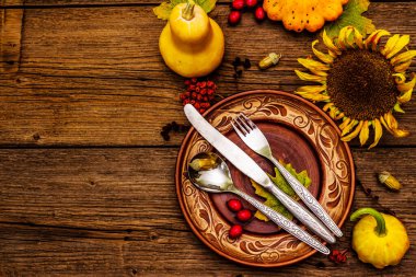 Sonbahar ve Şükran Günü yemeği. Balkabağı ve böğürtlen hasadı renkli yapraklar, seramik tabaklar, çatal, kaşık ve bıçak. Çatal bıçak takımı ahşap arka plan, üst görünüm