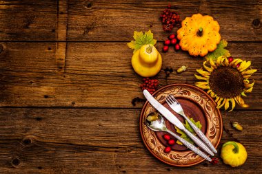 Sonbahar ve Şükran Günü yemeği. Balkabağı ve böğürtlen hasadı renkli yapraklar, seramik tabaklar, çatal, kaşık ve bıçak. Çatal bıçak takımı ahşap arka plan, üst görünüm