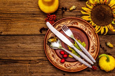 Sonbahar ve Şükran Günü yemeği. Balkabağı ve böğürtlen hasadı renkli yapraklar, seramik tabaklar, çatal, kaşık ve bıçak. Çatal bıçak takımı ahşap arka plan, üst görünüm