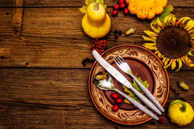 Sonbahar ve Şükran Günü yemeği. Balkabağı ve böğürtlen hasadı renkli yapraklar, seramik tabaklar, çatal, kaşık ve bıçak. Çatal bıçak takımı ahşap arka plan, üst görünüm