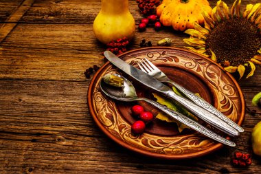 Sonbahar ve Şükran Günü yemeği. Balkabağı ve böğürtlen hasadı renkli yapraklar, seramik tabaklar, çatal, kaşık ve bıçak. Çatal bıçak takımı ahşap arkaplan, kopyalama alanı