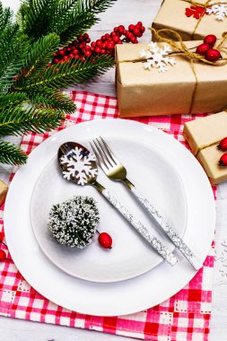 Noel ya da Yeni Yıl Atık Akşam Yemeği Yeri. Seramik tabaklar, hediye, kar taneleri, yaban mersini ve tematik dekor. Beyaz tahta arka planda şenlikli çatal bıçak seti, kapatın.