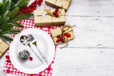 Noel ya da Yeni Yıl Atık Akşam Yemeği Yeri. Seramik tabaklar, hediye, kar taneleri, yaban mersini ve tematik dekor. Beyaz tahta arka plan, üst görünüm üzerinde şenlikli çatal bıçak seti