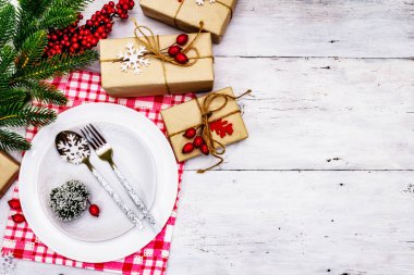 Noel ya da Yeni Yıl Atık Akşam Yemeği Yeri. Seramik tabaklar, hediye, kar taneleri, yaban mersini ve tematik dekor. Beyaz tahta arka plan, üst görünüm üzerinde şenlikli çatal bıçak seti