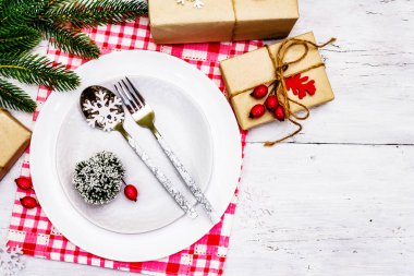 Noel ya da Yeni Yıl Atık Akşam Yemeği Yeri. Seramik tabaklar, hediye, kar taneleri, yaban mersini ve tematik dekor. Beyaz tahta arka plan, üst görünüm üzerinde şenlikli çatal bıçak seti
