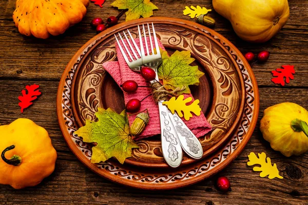 Sonbahar ve Şükran Günü yemeği. Balkabağı ve böğürtlen hasadı renkli yapraklar, seramik tabaklar, çatallar ve peçete. Çatal bıçak takımı ahşap arka plan, kapat