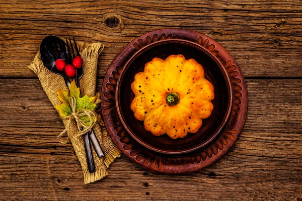 Sonbahar ve Şükran Günü yemeği. Balkabağı ve böğürtlen hasadı, renkli yapraklar, seramik tabaklar, çatal ve kaşık, antika peçete. Çatal bıçak takımı ahşap arka plan, üst görünüm