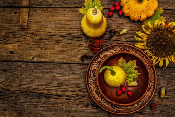 Sonbahar ve Şükran Günü yemeği. Balkabağı ve böğürtlen hasadı, renkli yapraklar, seramik tabak ve kase, ayçiçeği ve rowan. Çatal bıçak takımı ahşap arka plan