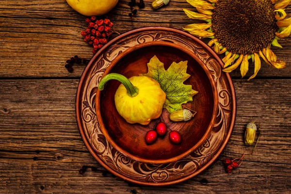 Sonbahar ve Şükran Günü yemeği. Balkabağı ve böğürtlen hasadı, renkli yapraklar, seramik tabak ve kase, ayçiçeği ve rowan. Çatal bıçak takımı ahşap arka plan