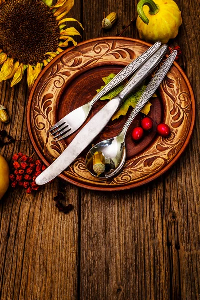 Sonbahar ve Şükran Günü yemeği. Balkabağı ve böğürtlen hasadı renkli yapraklar, seramik tabaklar, çatal, kaşık ve bıçak. Çatal bıçak takımı ahşap arkaplan, kopyalama alanı