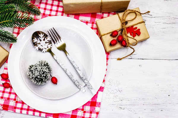 Noel ya da Yeni Yıl Atık Akşam Yemeği Yeri. Seramik tabaklar, hediye, kar taneleri, yaban mersini ve tematik dekor. Beyaz tahta arka plan, üst görünüm üzerinde şenlikli çatal bıçak seti