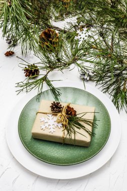 Noel ya da yeni yıl sofrası. Şenlikli çatal bıçak takımı, taze çam dallı seramik tabaklar, koniler, sıfır atık hediye ve yıldız anason. Beyaz macun arkaplanı, kapat