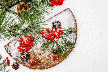 Kırmızı Rowan 'ın eski bir kar kaplı masada olduğu çam tümsekleri ve dallar. Geleneksel kış arkaplanı, kopyalama alanı