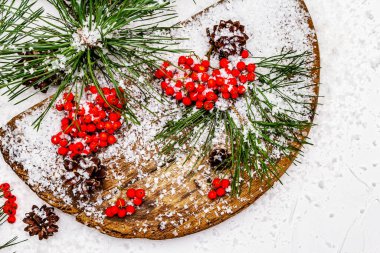 Kırmızı Rowan 'ın eski bir kar kaplı masada olduğu çam tümsekleri ve dallar. Geleneksel kış arkaplanı, kopyalama alanı