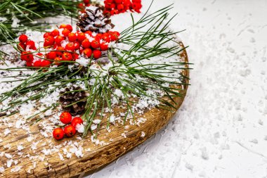 Kırmızı Rowan 'ın eski bir kar kaplı masada olduğu çam tümsekleri ve dallar. Geleneksel kış arkaplanı, kopyalama alanı