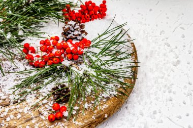 Kırmızı Rowan 'ın eski bir kar kaplı masada olduğu çam tümsekleri ve dallar. Geleneksel kış arkaplanı, kopyalama alanı