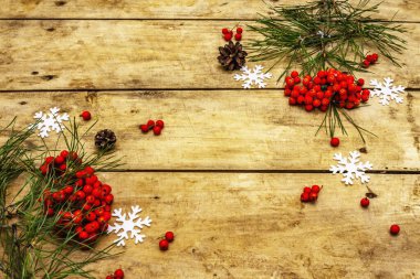 Noel ya da yeni yıl konsepti. Taze çam dalları, olgun yaban mersini, kar taneleri ve çam kozalakları. Eski ahşap zemin, üst manzara