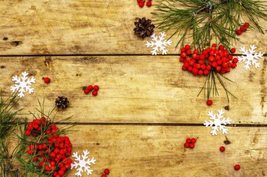 Noel ya da yeni yıl konsepti. Taze çam dalları, olgun yaban mersini, kar taneleri ve çam kozalakları. Eski ahşap zemin, üst manzara