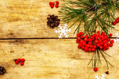 Noel ya da yeni yıl konsepti. Taze çam dalları, olgun yaban mersini, kar taneleri ve çam kozalakları. Eski ahşap zemin, üst manzara