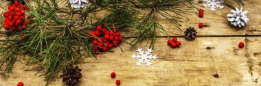 Noel ya da yeni yıl konsepti. Taze çam dalları, olgun yaban mersini, kar taneleri ve çam kozalakları. Eski ahşap arkaplan, pankart biçimi