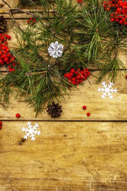 Noel ya da yeni yıl konsepti. Taze çam dalları, olgun yaban mersini, kar taneleri ve çam kozalakları. Eski ahşap zemin, üst manzara