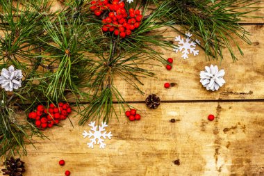 Noel ya da yeni yıl konsepti. Taze çam dalları, olgun yaban mersini, kar taneleri ve çam kozalakları. Eski ahşap zemin, üst manzara