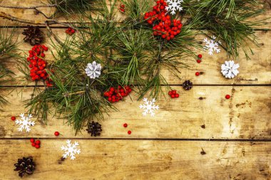 Noel ya da yeni yıl konsepti. Taze çam dalları, olgun yaban mersini, kar taneleri ve çam kozalakları. Eski ahşap zemin, üst manzara