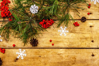 Noel ya da yeni yıl konsepti. Taze çam dalları, olgun yaban mersini, kar taneleri ve çam kozalakları. Eski ahşap zemin, üst manzara